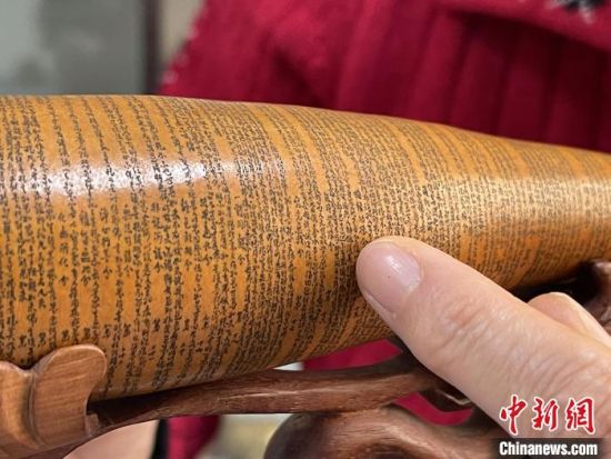 圖為長約二十公分的長條葫蘆雕刻佛教經文作品。　張婧 攝