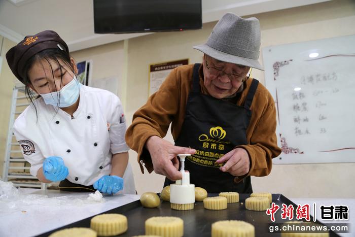 當日，受邀參加活動的臺胞臺屬代表、兩岸婚姻及子女、在甘臺商代表等歡聚一堂。圖為77歲的在甘臺胞潘天鑒制作月餅。九美旦增 攝