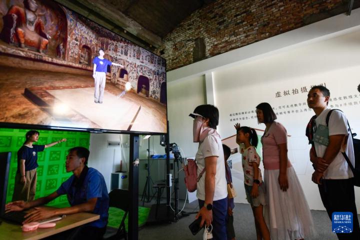 7月22日，游客體驗“尋境敦煌——數(shù)字敦煌沉浸展”后，在虛擬演播廳拍攝一段真人與洞窟虛擬場景交互的視頻。新華社記者 郎兵兵 攝</p>
<p>