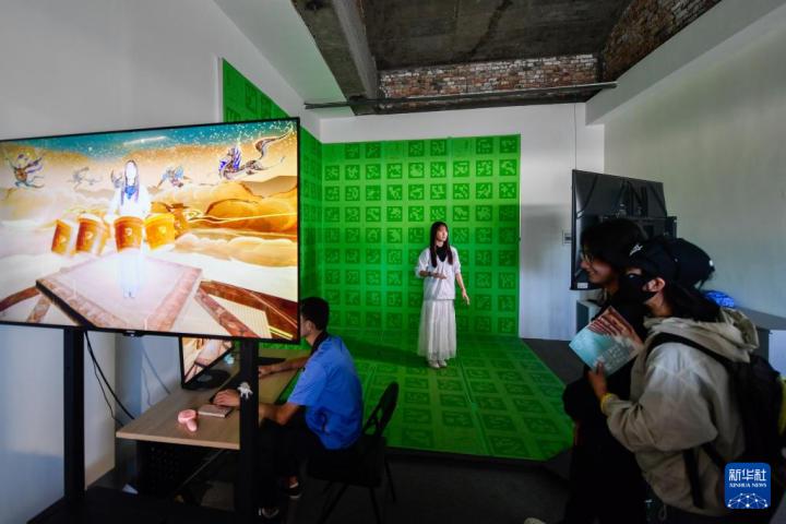7月22日，游客體驗“尋境敦煌——數(shù)字敦煌沉浸展”后，在虛擬演播廳拍攝一段真人與洞窟虛擬場景交互的視頻。新華社記者 郎兵兵 攝</p>
<p>